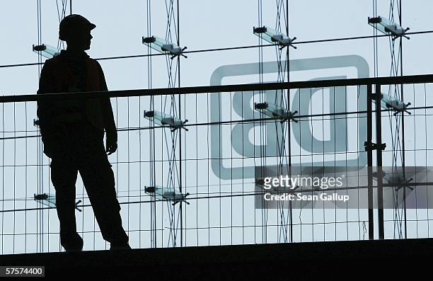 Worker is silhoutted in front of the logo of German railways company Deutsche Bahn May 10, 2006 at the nearly-completed Hauptbahnhof railway station...