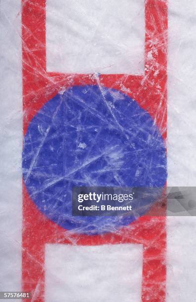 Overhead view of the face-off circle in the center of an ice hockey rink shows the scratches of use, late 20th Century.