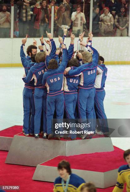 Members of the American Men's Olympic ice hockey team make the 'We're number one' gesture as they celebrate on the medal podium after receiving their...