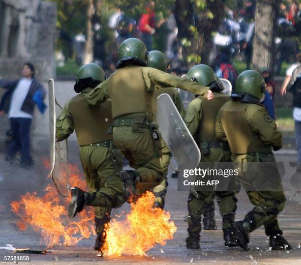 Policia de las fuerzas especiales chilenas saltan para evitar algunas bombas incendiarias durante una protesta en Santiago de 10 de mayo de 2006. La...