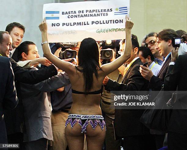 Greenpeace demonstrator wearing a bikini shows a banner to media against pulp mills plants installation in Fray Bentos, Uruguay over the shores of...