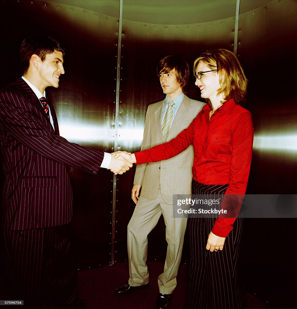 Side profile of a young businessman shaking hands with a young businesswoman