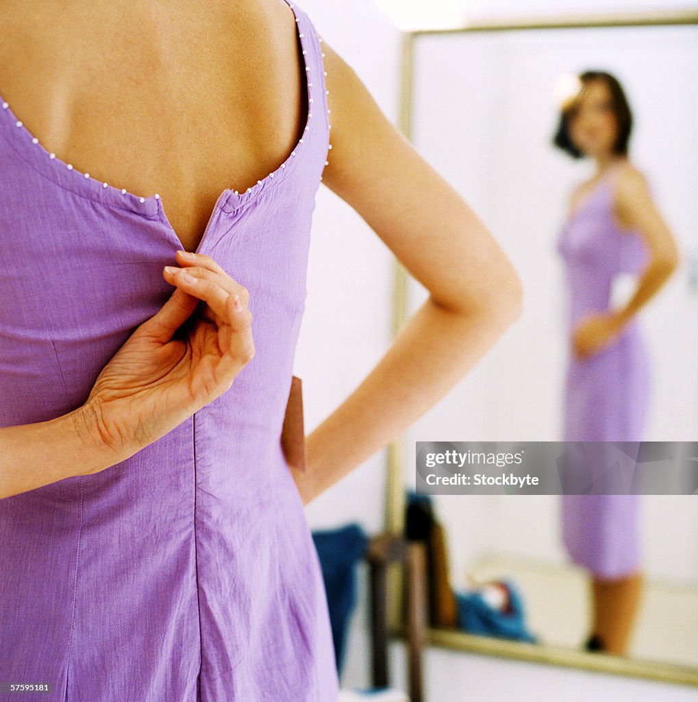 A young woman zipping up her dress