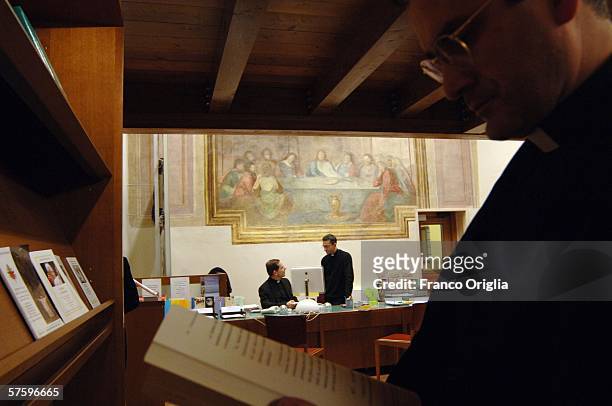 Priests of Opus Dei talk in front of a painting featuring "The Last Supper" at the library of the Holy Cross University, December 15 in Rome, Italy....