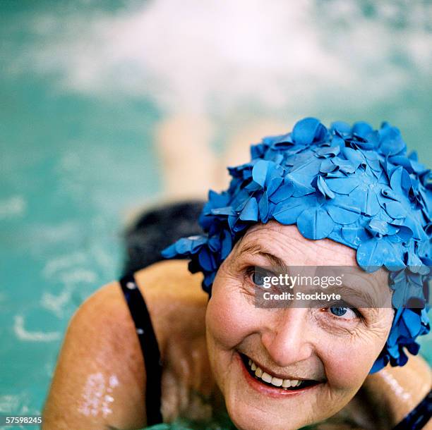 elderly woman swimming in swimming pool wearing a swimming cap - swimming cap stock pictures, royalty-free photos & images