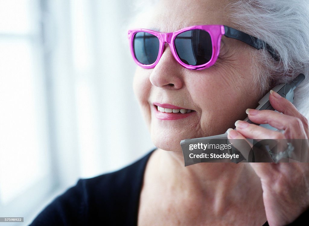 Portrait of an elderly woman wearing sunglasses talking on a mobile phone