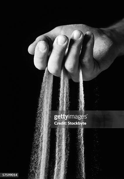 black and white close-up a hand with sand streaming through the fingers - sifting stock pictures, royalty-free photos & images