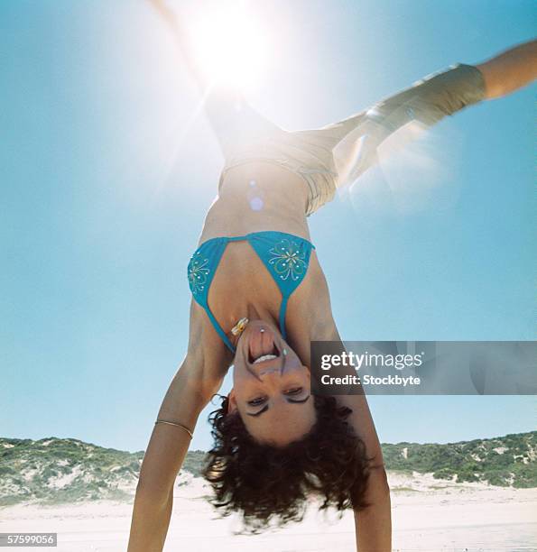 close-up of a woman in a bikini doing a handstand on the beach - cartwheel stock pictures, royalty-free photos & images