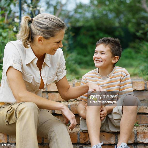 mother putting a plaster on her son's knee (10-11) - knees together - fotografias e filmes do acervo
