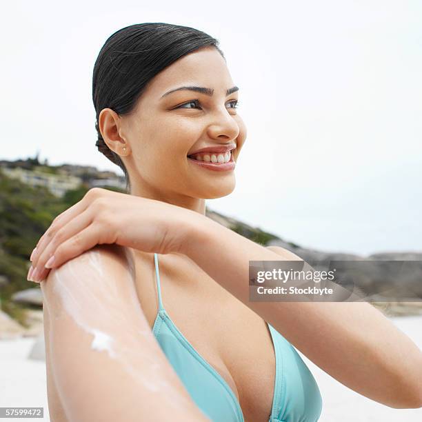 front view portrait of a woman applying sun cream to her face - arm sun beach stock-fotos und bilder