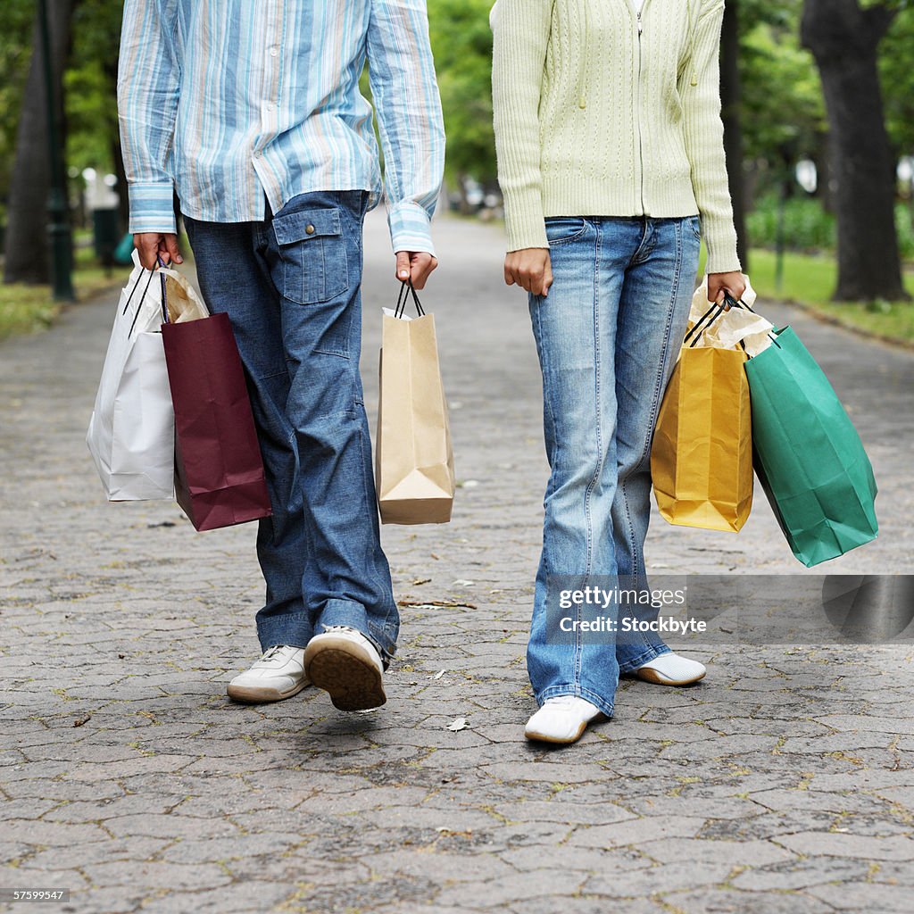 Low section of a couple carrying shopping bags