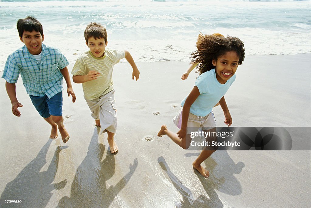 High angle view of three children running on the beach