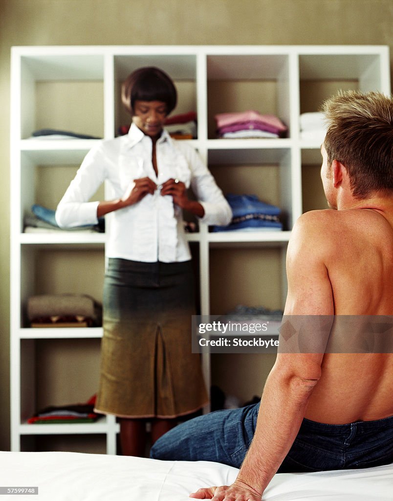 Rear view of a young man watching a young woman get dressed
