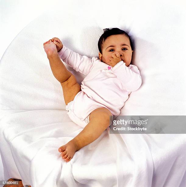 elevated view of a baby (12-18 months) holding his feet - leg stretch girl stock-fotos und bilder