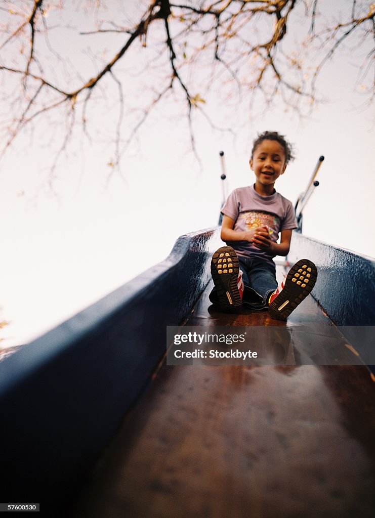 Low angle view of a young girl (4-6) coming down a slide