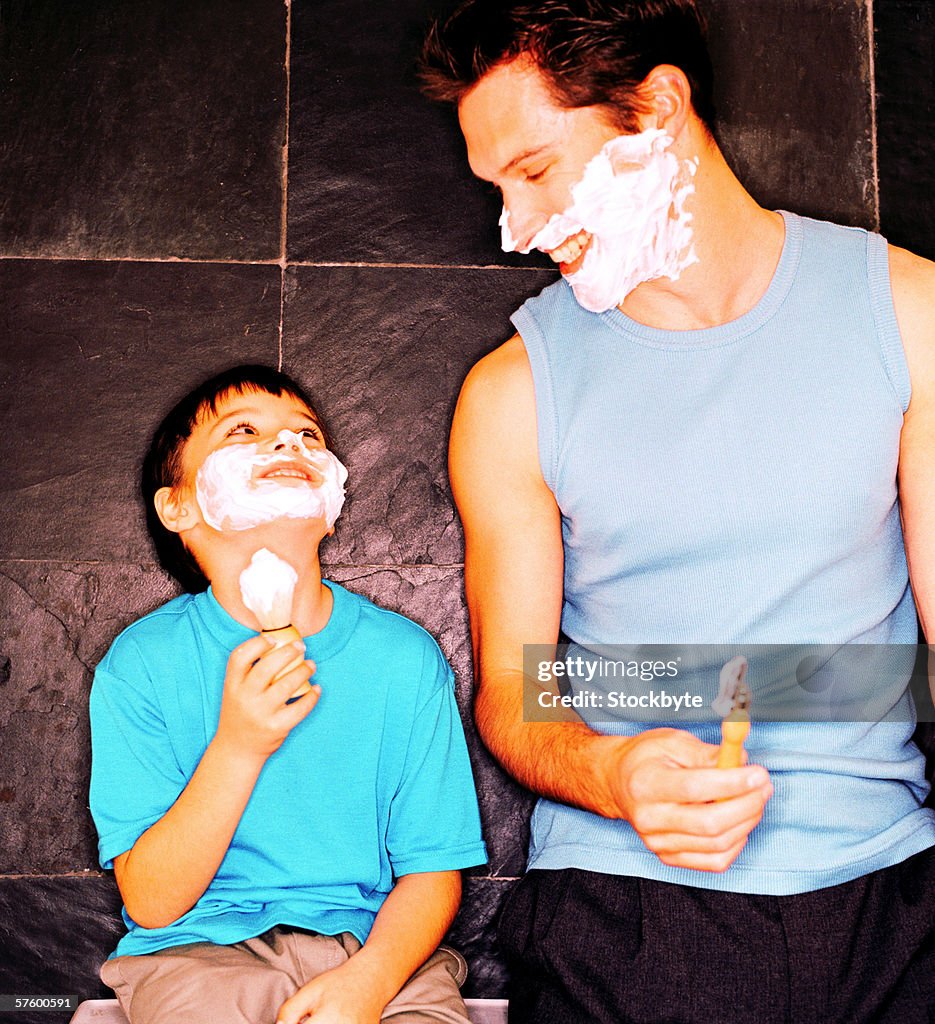 Young boy (6-8) pretending to shave with his father
