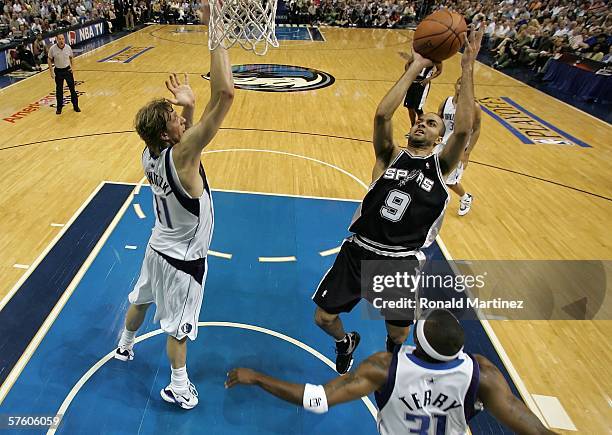 Tony Parker of the San Antonio Spurs drives for a shot attempt against Dirk Nowitzki and Jason Terry of the Dallas Mavericks in Game three of the...