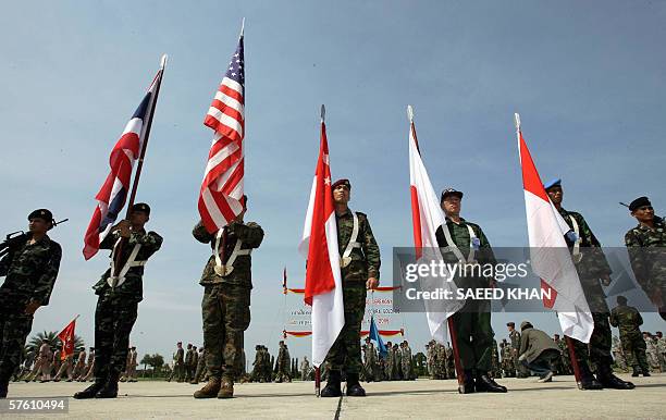 Flag carriers of participating countries stand in formation as troops march in the background during the opening ceremony for the Cobra Gold military...