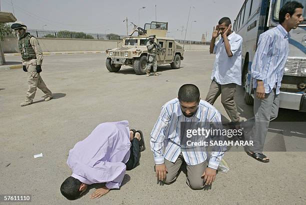 Iraqi freed prisoners pray in front of US soldiers in central Baghdad upon their release, 15 May 2006. More than 100 Iraqi priosners were freed from...