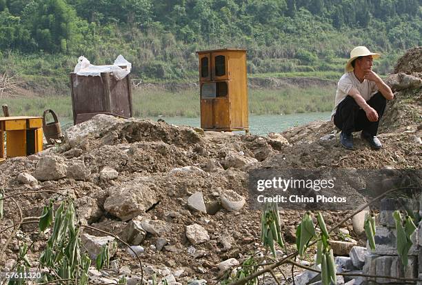 Man squats at ruins of demolished houses on May 14, 2006 in Dachang Township of Chongqing Municipality, China. Dachang Township is an ancient town...