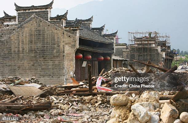 Workers in the distance demolish old houses on May 14, 2006 in Dachang Township of Chongqing Municipality, China. Dachang Township is an ancient town...