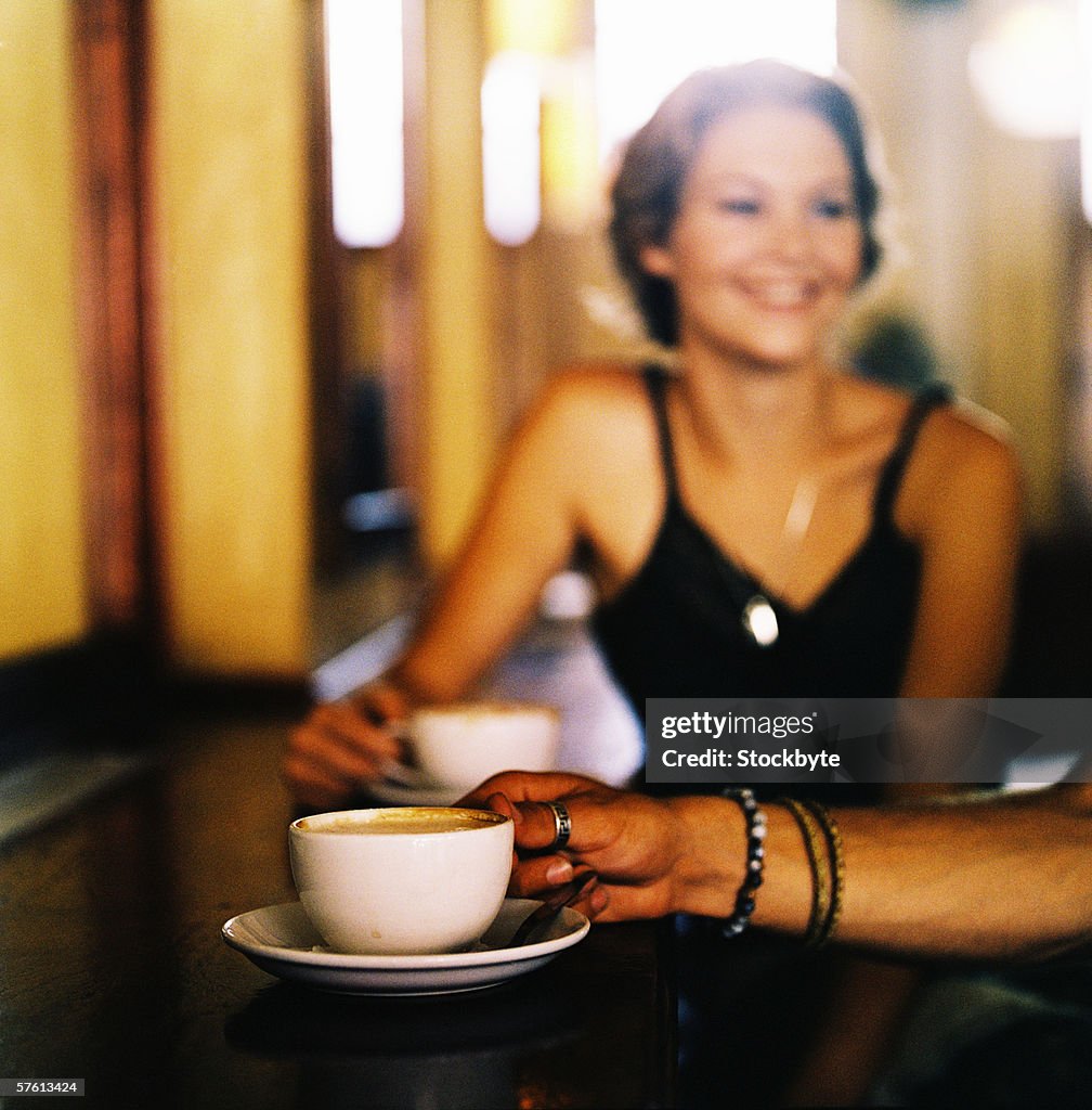 Close-up of the hand of a man picking up a cup of coffee