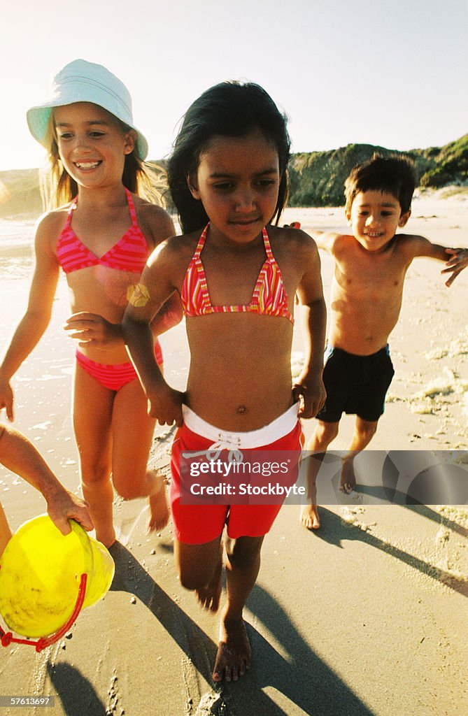 Two young girls and a young boy (4-8) playing at the beach