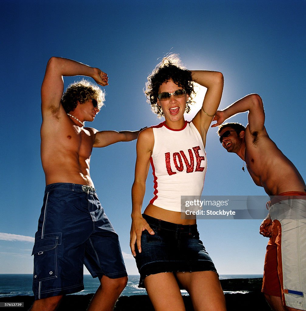 Young woman dancing on the beach with two young men