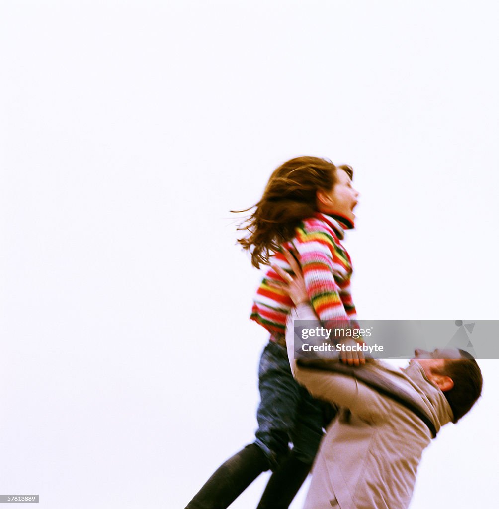 Young man throwing a young girl (6-8) up in the air