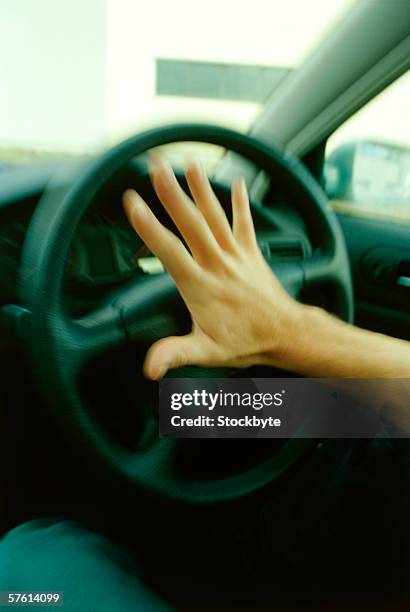 close-up of a human hand pressing the horn of a car (blurred) - car horn stock-fotos und bilder