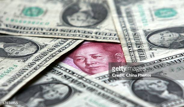 Dollars and yuan notes are seen at a bank on May 15, 2006 in Beijing, China. China's official exchange rate rose today to 7.9982 yuan per U.S....