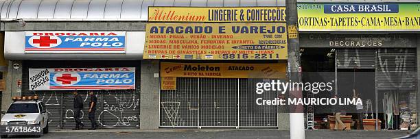 Employees close down the shutter of a carpet shop as a couple of private security personnel guard closed stores due a suspecious information about...