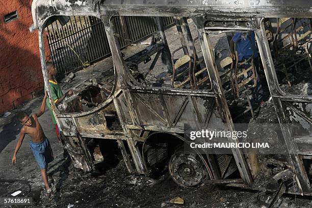 Boys play around an attacked bus burned with molotov cocktails by gang members in Campo Limpo neighborhood, a south area of Sao Paulo, Brazil, 15 May...