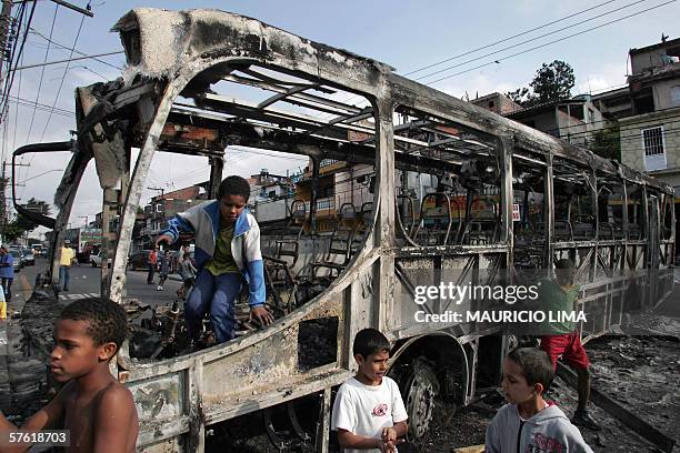 Boys play around an attacked bus burned with molotov cocktails by gang members in Campo Limpo neighborhood, a south area of Sao Paulo, Brazil, 15 May...