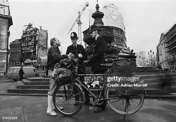 German round-the-world cyclist Heinz Stucke chats with two policemen by the statue of Eros in London's Piccadilly Circus, 1977.