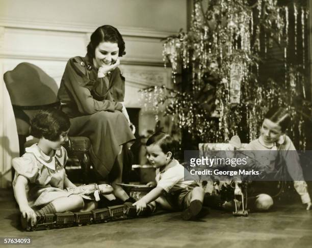 madre viendo tres niños jugando con árbol de navidad, (b & p - 1940s fotografías e imágenes de stock