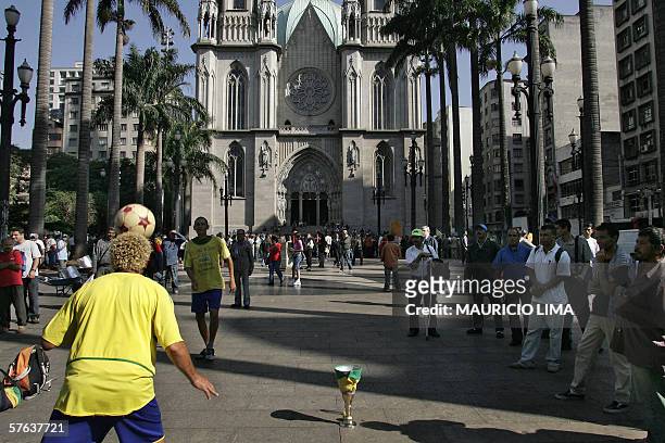 Couple of street artists, wearing T-shirts of the Brazilian national soccer team, perform in front of the Se cathedral, the day after the worst wave...