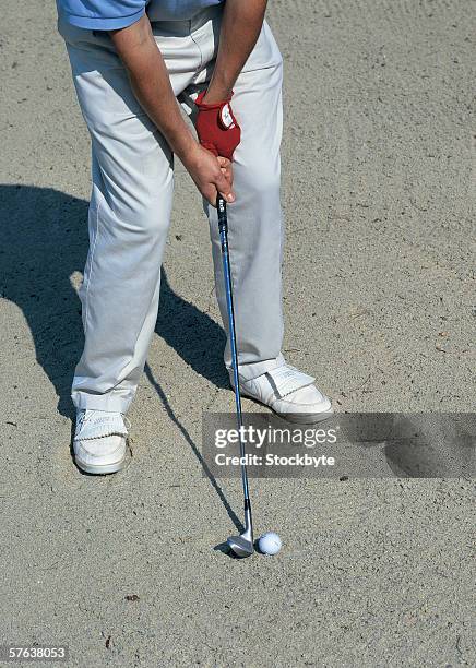 high angle view of a golfer as he prepares to hit the ball from a sand pit - adult ball pit stock-fotos und bilder