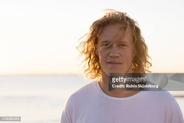 portrait of young man with long hair in sunset - blonde man stockfoto's en -beelden