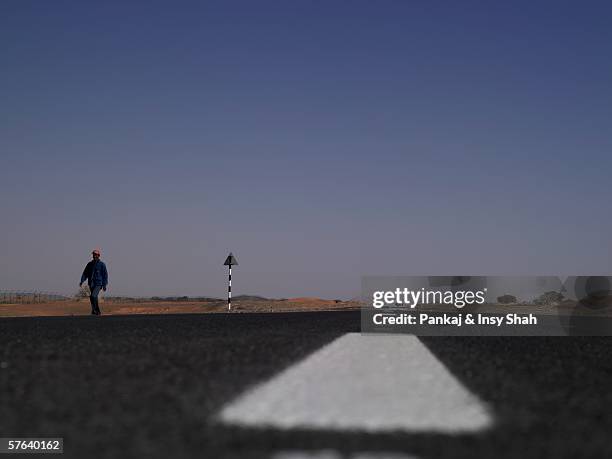 one man walking on a desert road - two way traffic sign stock pictures, royalty-free photos & images