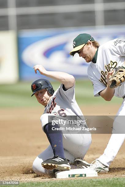 Chris Shelton of the Detroit Tigers slides into first base against Dan Johnson of the Oakland Athletics at the Network Associates Coliseum in...