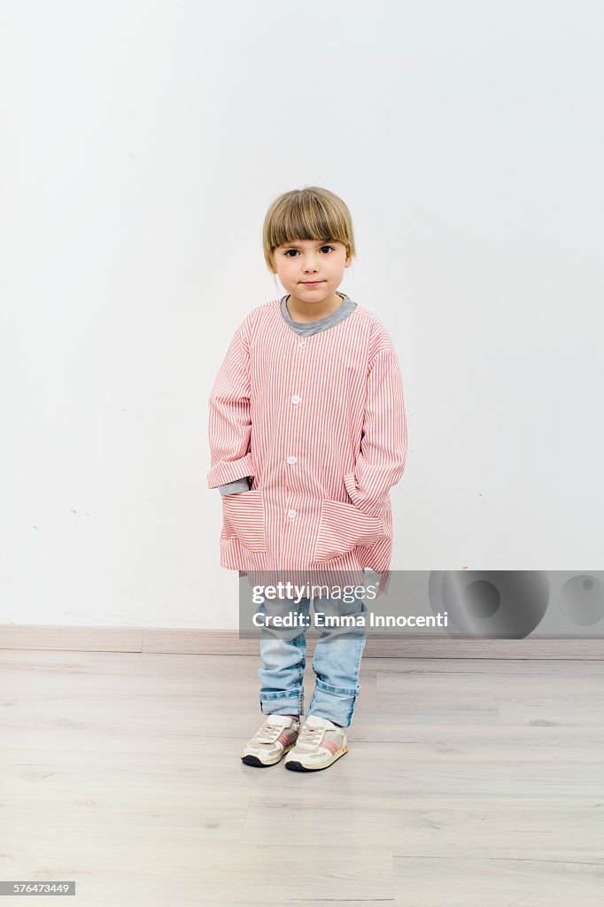 Girl standing wearing nursery school apron