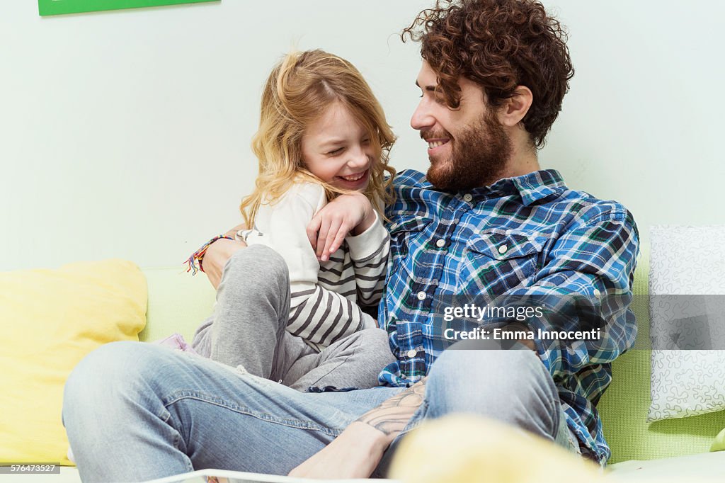 Dad and daughter playing and cuddling on sofa