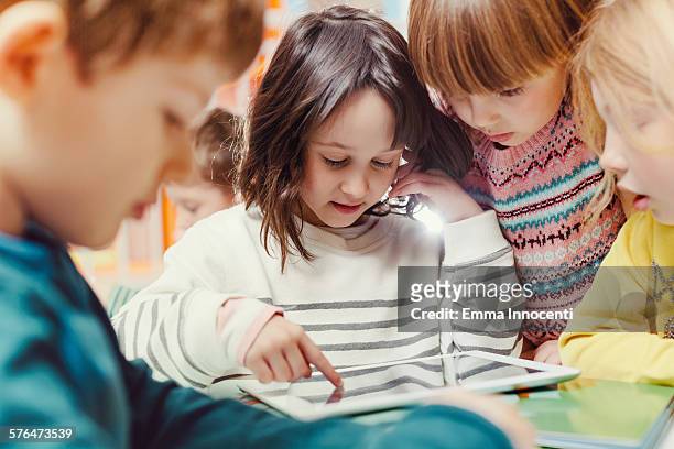girl using tablet in classroom with friends - kinder lernen spaß stock-fotos und bilder