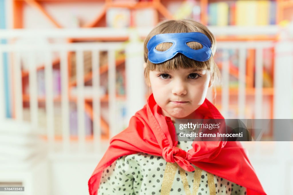 Girl in spotty jumper with superhero mask and cape