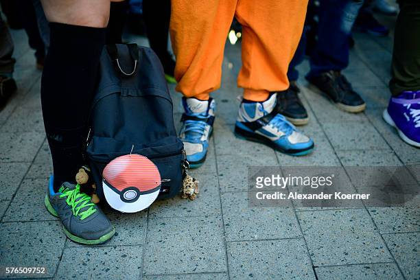 The feet and bags of young players are seen standing in the city centre of Hanover while holding their smartphones and playing "Pokemon Go" on July...