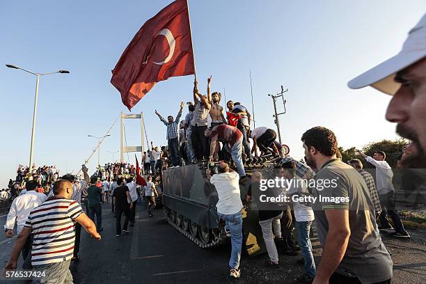 Supporters of Turkish President Recep Tayyip Erdogan wave flags as they capture a Turkish Army APC after soldiers involved in the coup attempt have...