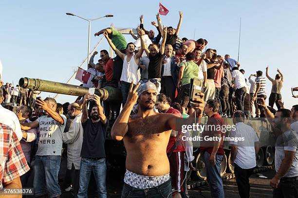 Supporters of Turkish President Recep Tayyip Erdogan wave flags as they capture anTurkish Army APC after soldiers involved in the coup surrendered on...