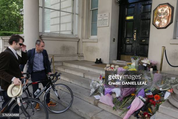 People look at flowers placed in solidarity outside the French embassy in London on July 16 following the July 14 attack in the southern French city...