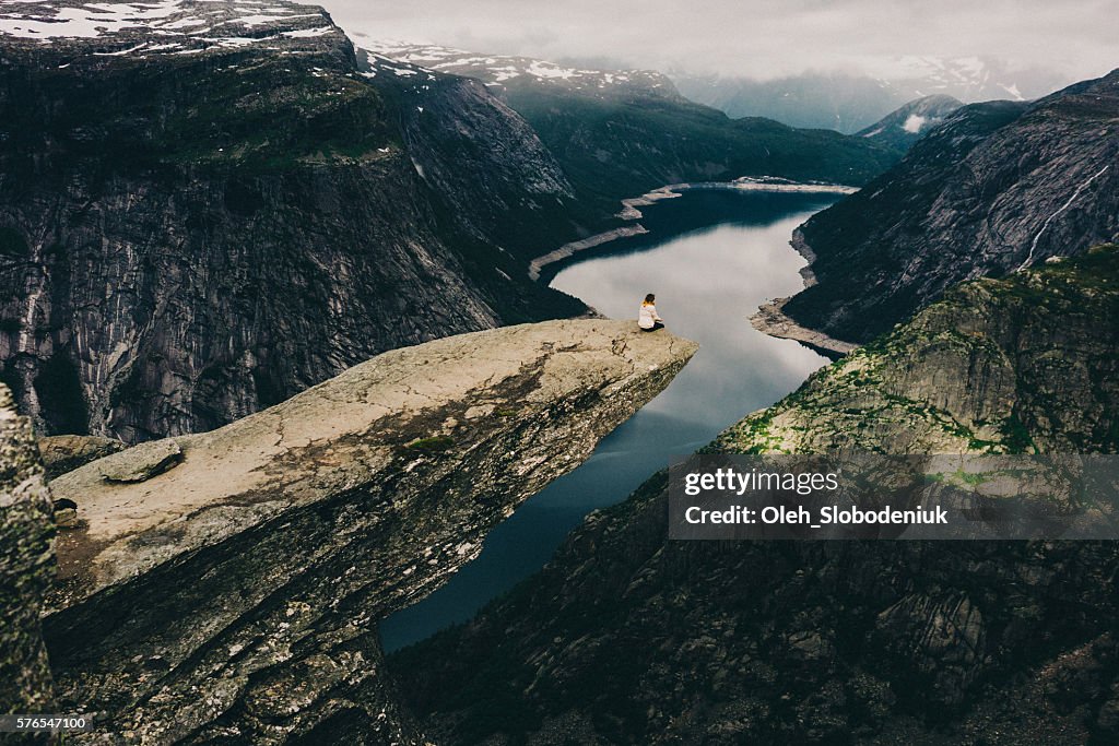 Frau sitzt auf Trolltunga